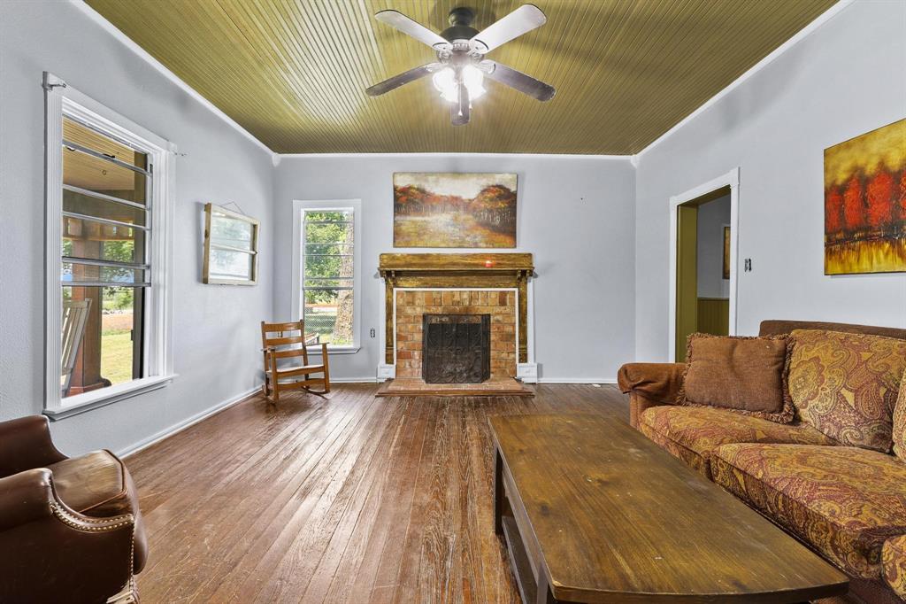 4453 Farm To Market 902 Howe, TX 75459 - Photo 11 of 40 Spacious living area featuring wood-finish flooring, a brick fireplace with a wood mantel, and multiple windows