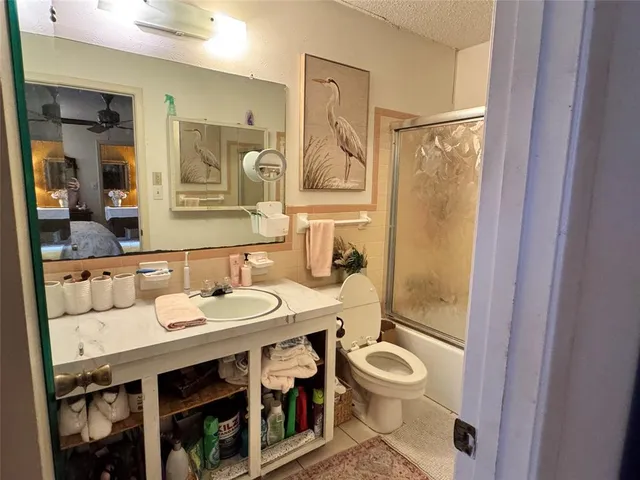 a bathroom with a granite countertop a sink a toilet a mirror and shower