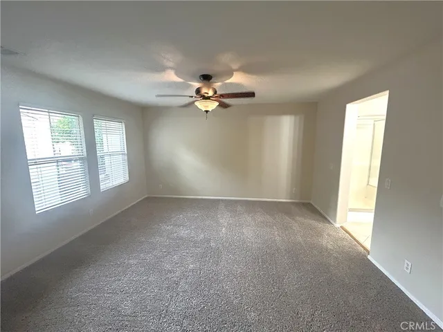 an empty room with chandelier fan and windows