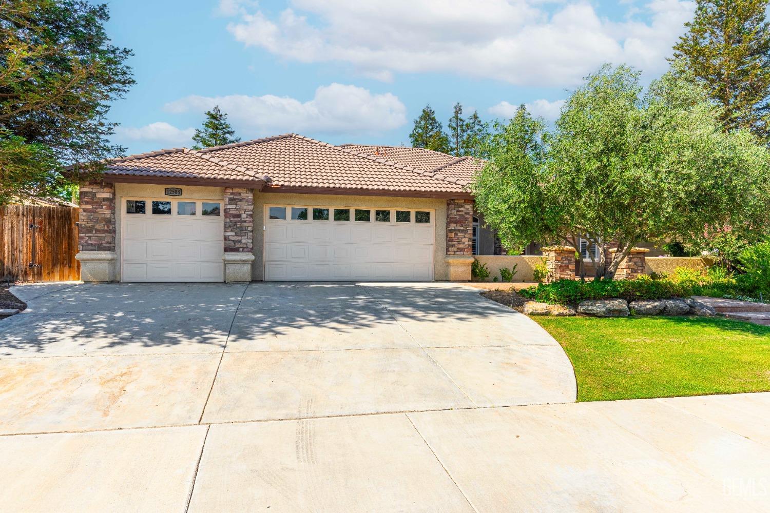 Undisclosed Address Bakersfield, CA 93312 - Photo 8 of 51 a view of a white house with a yard plants and large tree