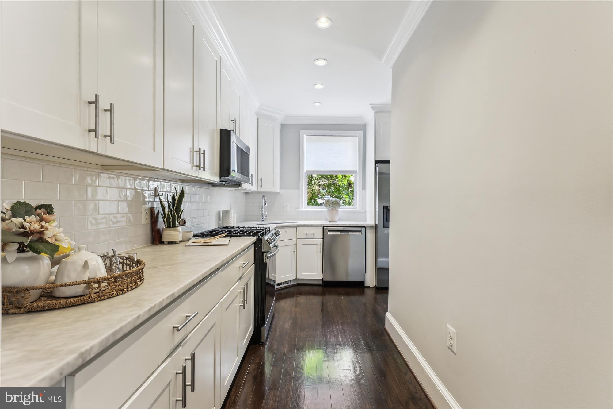 1406 Foxhall Road Northwest Washington, DC 20007 - Photo 9 of 41 a kitchen with a sink dishwasher stove and white cabinets with wooden floor