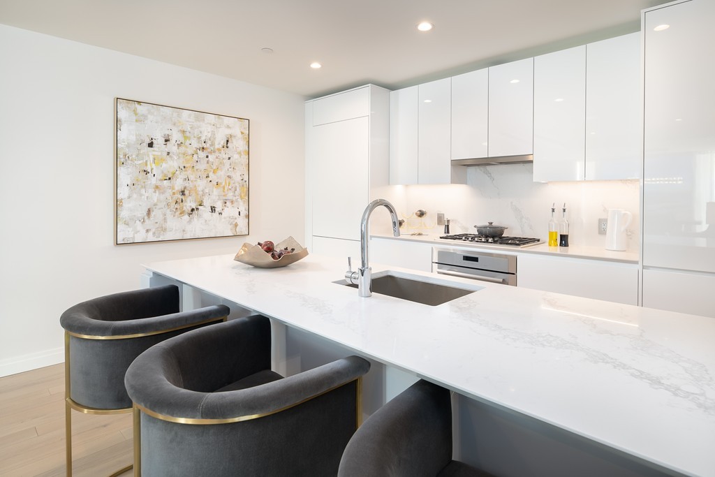 133 Seaport Boulevard, Unit 1017 Boston, MA 02210 - Photo 5 of 17 a kitchen with stainless steel appliances kitchen island a table and chairs