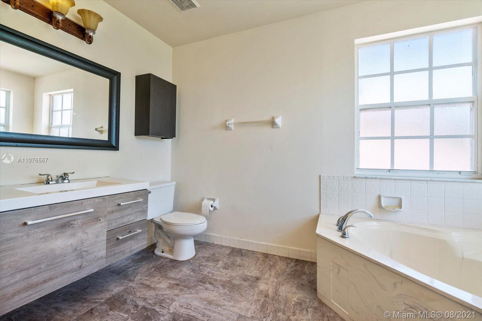 153 Granada Avenue Weston, FL 33326 - Photo 19 of 37 a bathroom with a bathtub sink mirror vanity and toilet