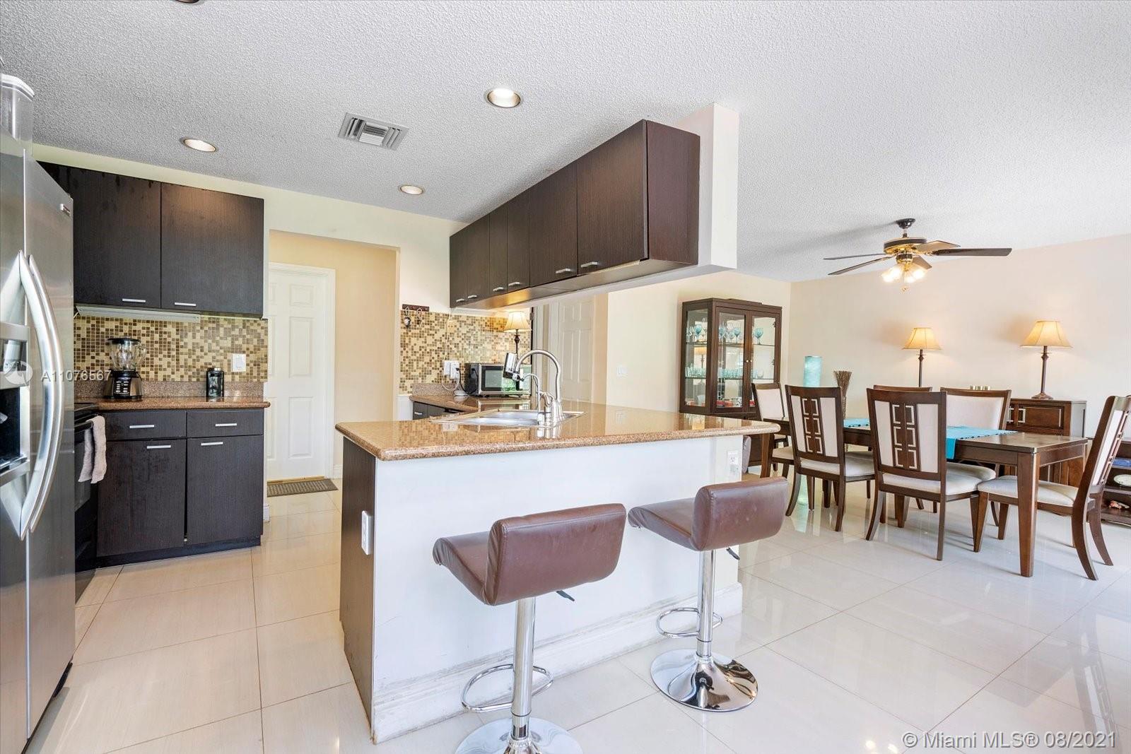 153 Granada Avenue Weston, FL 33326 - Photo 8 of 37 a kitchen with stainless steel appliances kitchen island granite countertop a refrigerator and cabinets
