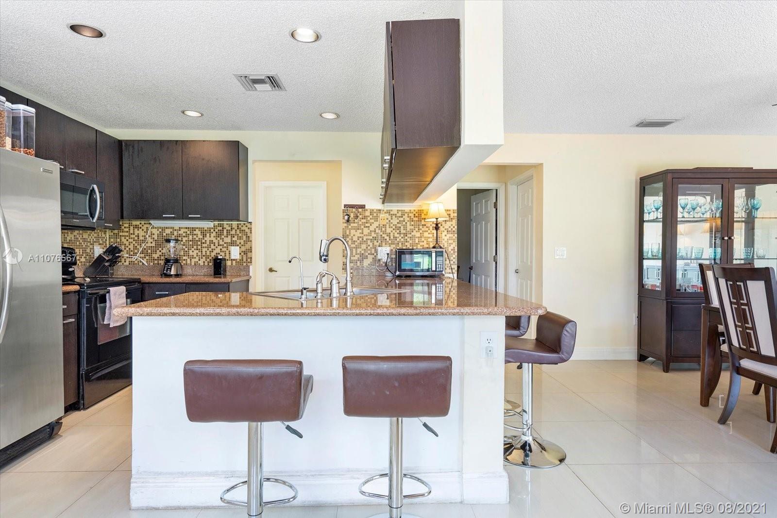 153 Granada Avenue Weston, FL 33326 - Photo 9 of 37 a kitchen with stainless steel appliances kitchen island granite countertop a refrigerator and a stove top oven