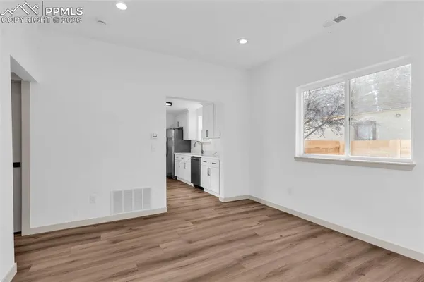 a view of empty room with wooden floor and windows