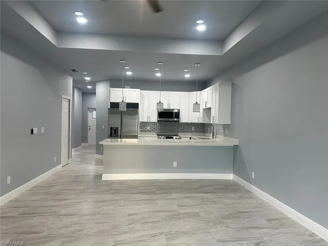a view of kitchen with stainless steel appliances granite countertop refrigerator sink and cabinets