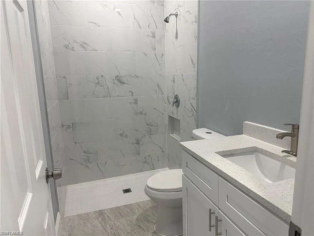 742 Eisenhower Boulevard Lehigh Acres, FL 33974 - Photo 9 of 11 a bathroom with a sink a toilet and shower