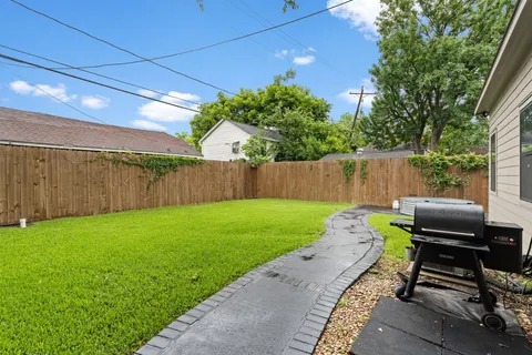 a view of a backyard with chairs potted plants and a large tree