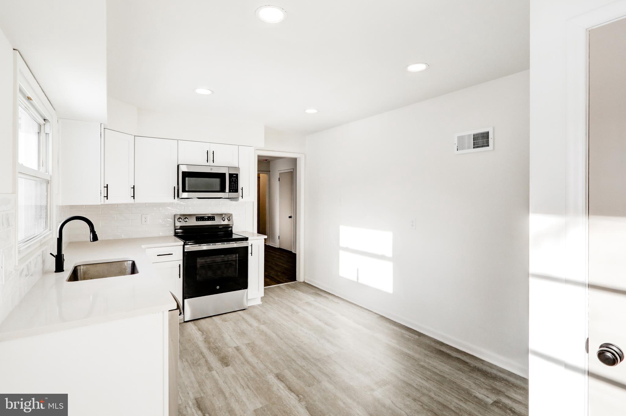 163 Thomas Place Reading, PA 19608 - Photo 13 of 36 a kitchen with stainless steel appliances granite countertop a stove a sink a refrigerator and white cabinets with wooden floor