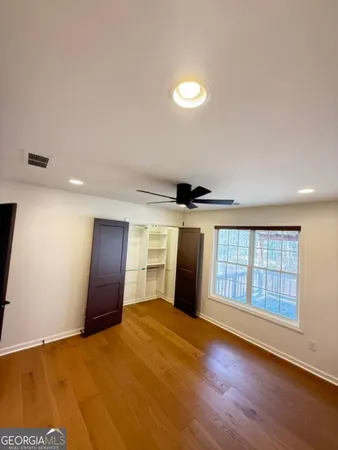 an empty room with windows and ceiling fan