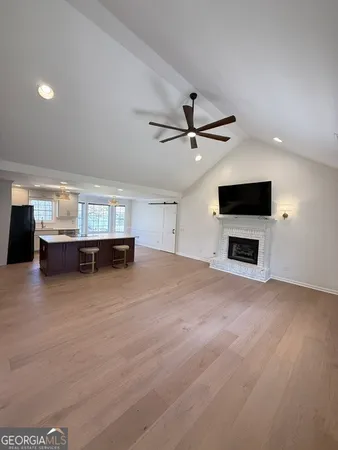 a view of a livingroom with a flat screen tv wooden floor and a ceiling fan
