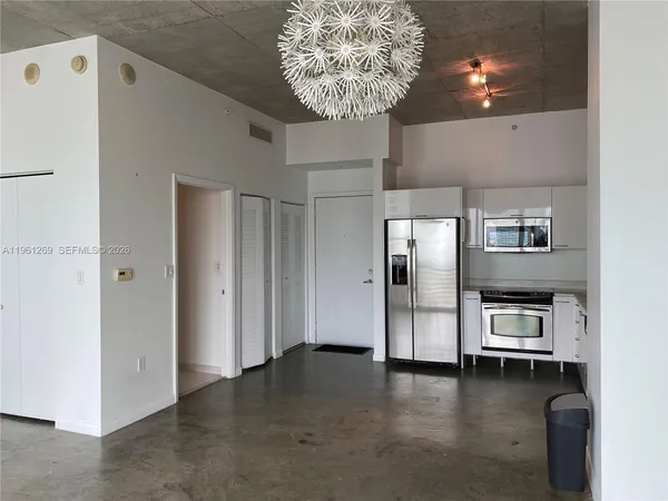 an empty room with wooden floor and windows with curtains