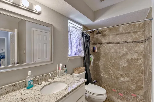 a bathroom with a granite countertop sink toilet a mirror and shower