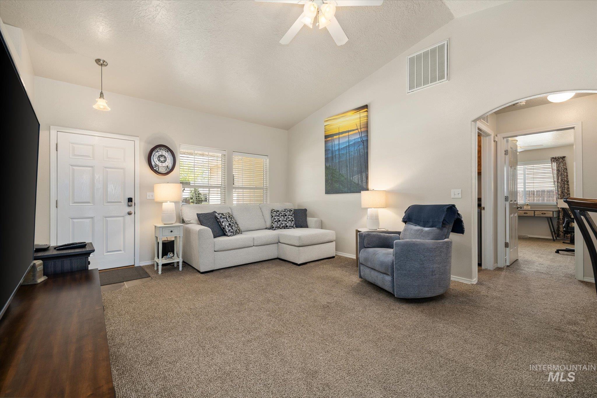5401 Barkley Way Caldwell, ID 83607 - Photo 16 of 35 Expansive carpeted living area featuring vaulted ceilings, a ceiling fan, and multiple windows with blinds