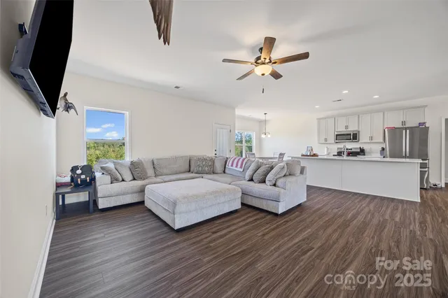 a living room with couches a flat screen tv and kitchen view