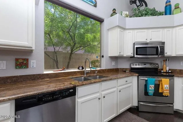 a kitchen with stainless steel appliances granite countertop a sink a stove a microwave and wooden cabinets
