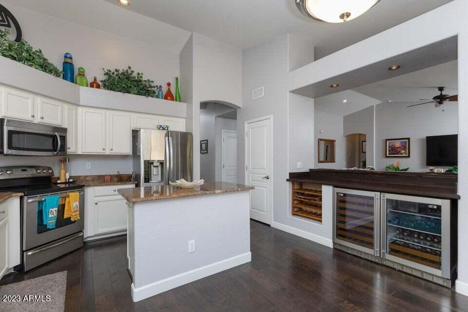 7338 East Wingspan Way Scottsdale, AZ 85255 - Photo 12 of 32 a kitchen with stainless steel appliances granite countertop a stove top oven a sink a refrigerator white cabinets and wooden floor