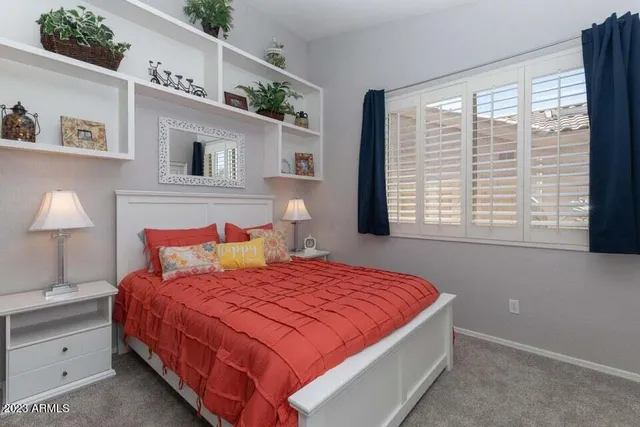 a bedroom with a large bed and a lamp on dresser