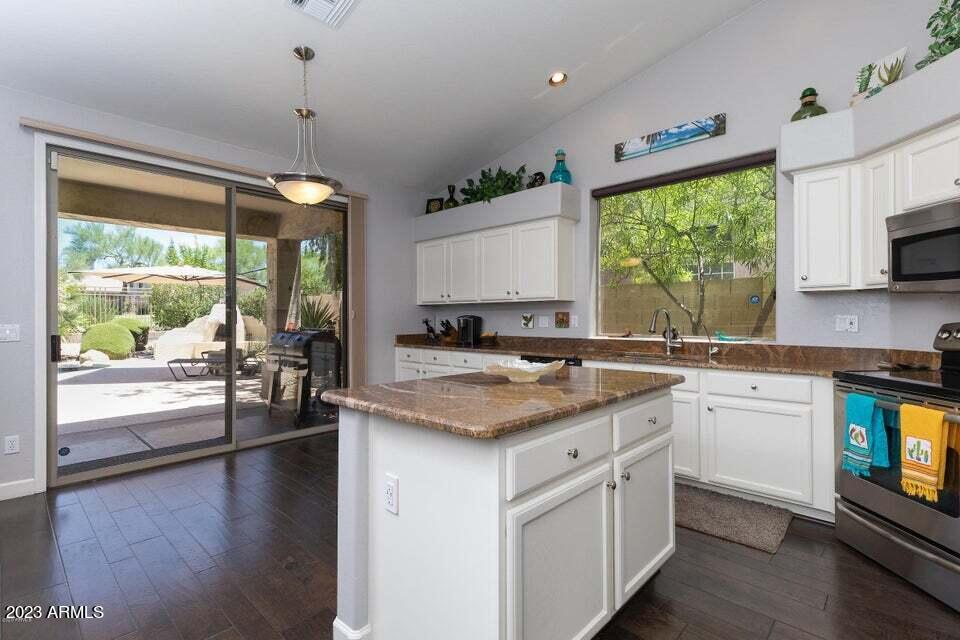 7338 East Wingspan Way Scottsdale, AZ 85255 - Photo 10 of 32 a kitchen with a stove a sink a center island and wooden floor