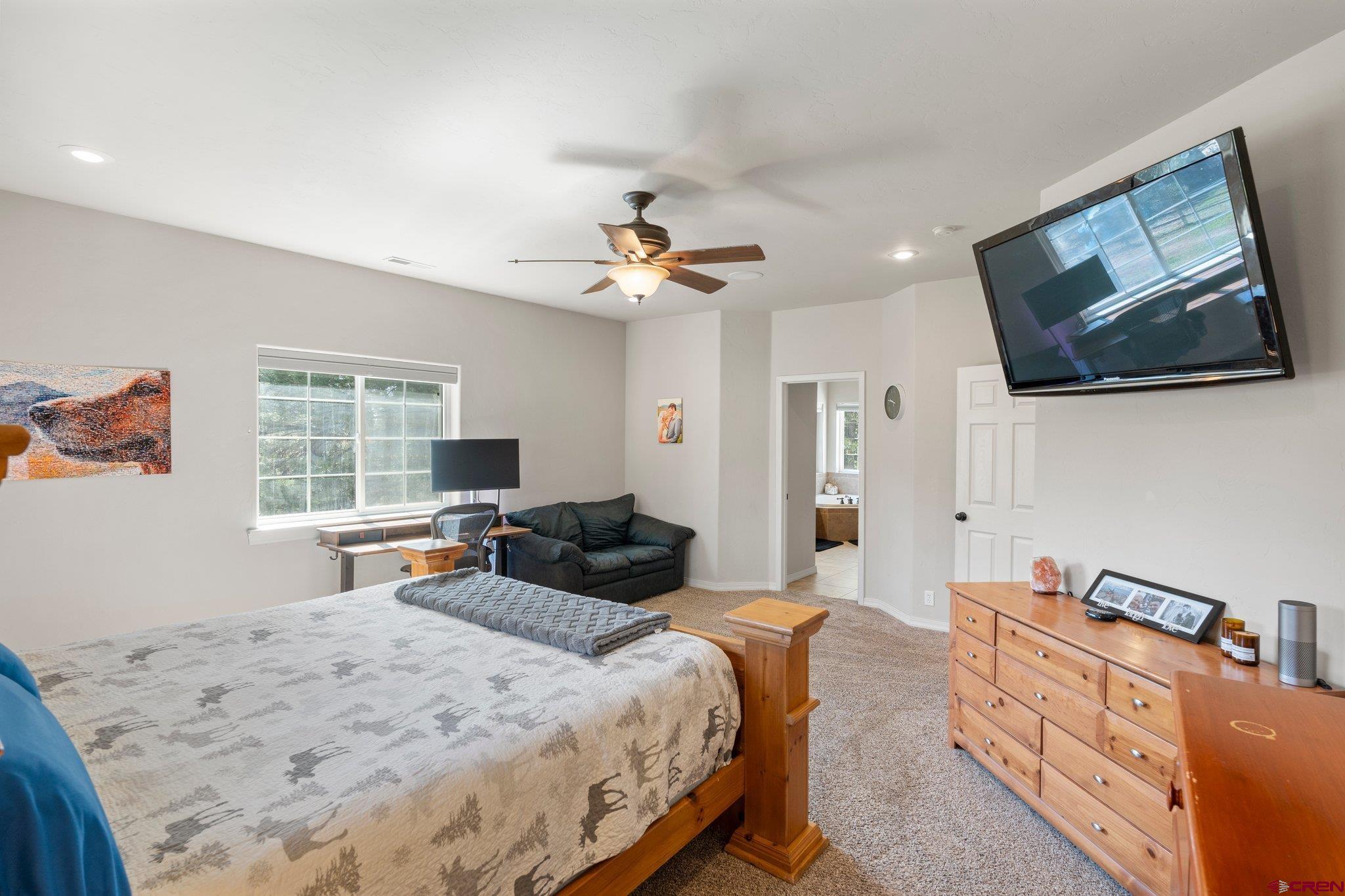 23 Hunter Court Durango, CO 81301 - Photo 24 of 42 a spacious bedroom with a bed a couch and a flat tv screen on the dresser