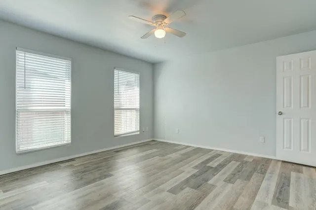 a view of empty room with wooden floor and fan