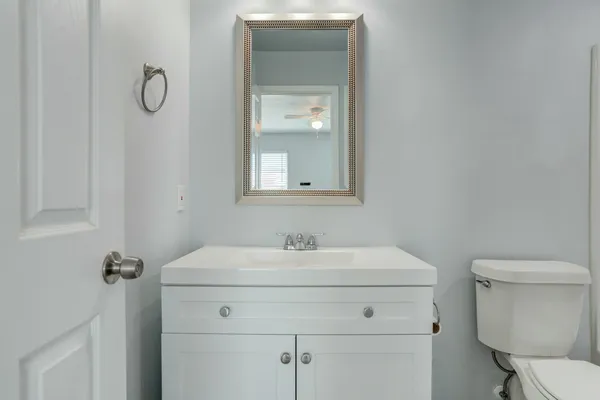 a bathroom with a toilet sink vanity and mirror