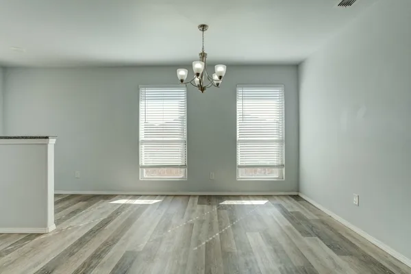an empty room with wooden floor exposed radiator and windows