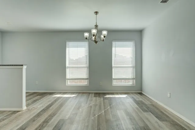 an empty room with wooden floor exposed radiator and windows
