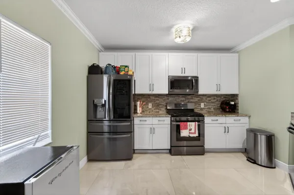 a kitchen with granite countertop a refrigerator and a stove top oven