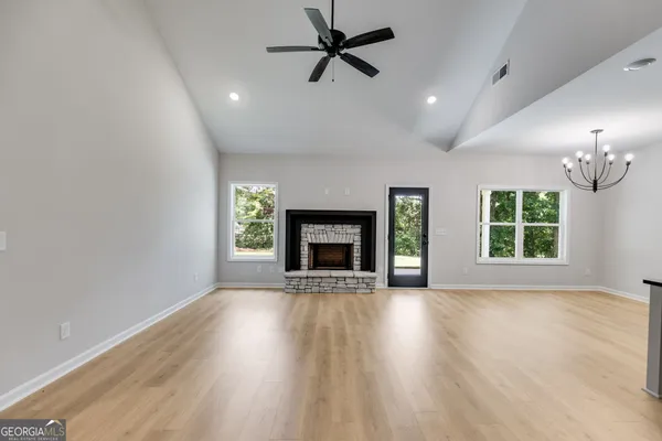 an empty room with windows fireplace and a kitchen view