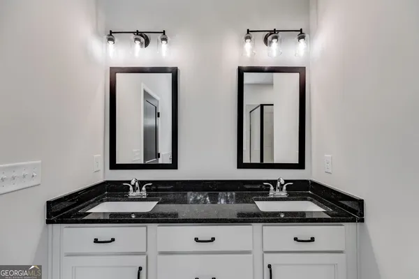 a bathroom with double sink and two mirror