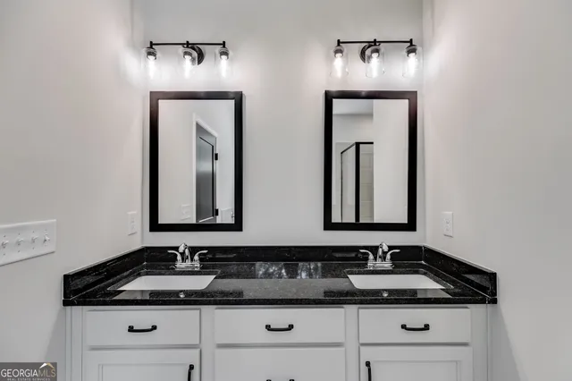 a bathroom with double sink and two mirror