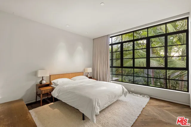 a bed sitting in a spacious bedroom next to a window