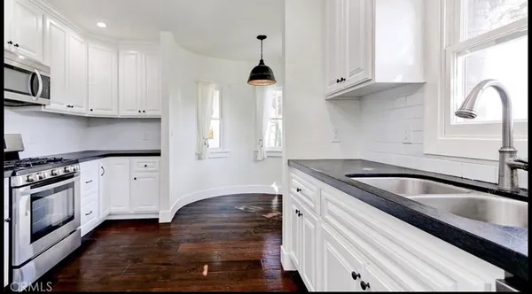 a kitchen with granite countertop a sink stove and cabinets