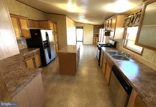 a kitchen with stainless steel appliances granite countertop sink stove refrigerator and cabinets