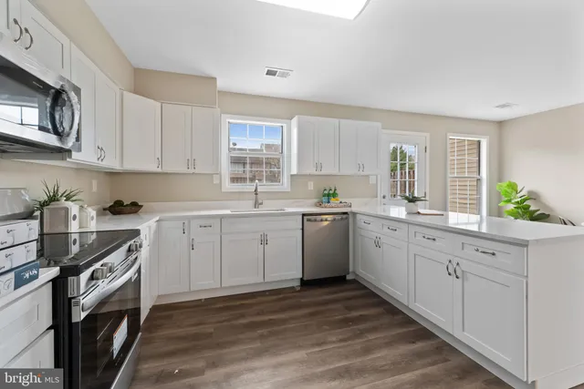 a large white kitchen with wooden floor and a window