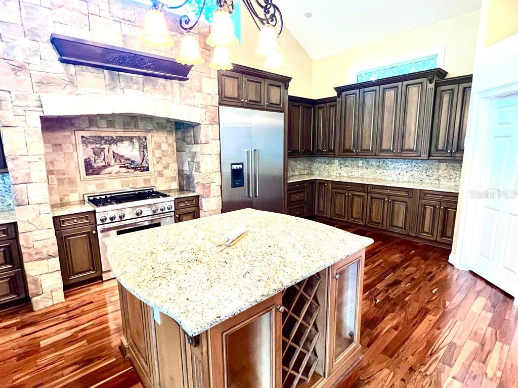 5610 West Lake Butler Road Windermere, FL 34786 - Photo 30 of 32 a kitchen with kitchen island granite countertop wooden cabinets a stove and a sink
