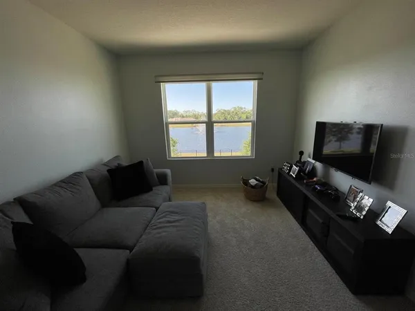a living room with furniture a flat screen tv and a window
