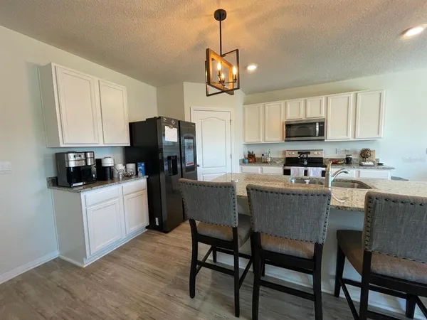 a kitchen with stainless steel appliances granite countertop a table chairs microwave and sink