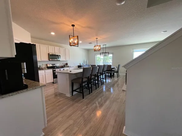 a kitchen with stainless steel appliances a dining table chairs and granite counter tops