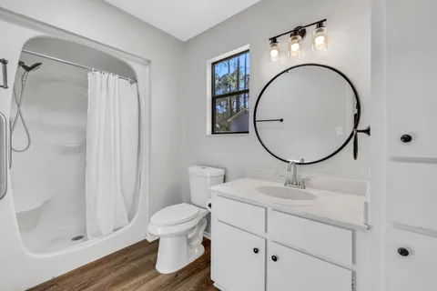 a view of a bathroom with wooden floor and mirror