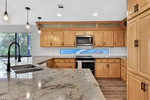 a kitchen with granite countertop a stove top oven sink and cabinets