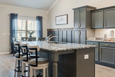 a kitchen with granite countertop a table chairs stove and cabinets