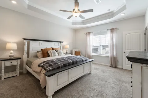 a bed sitting in a spacious bedroom next to a window and a chandelier
