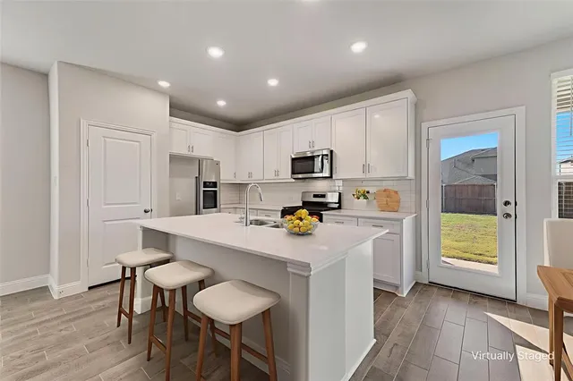 a kitchen with a sink a stove a refrigerator cabinets and wooden floor