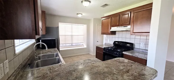 a kitchen with granite countertop a stove a sink and a refrigerator