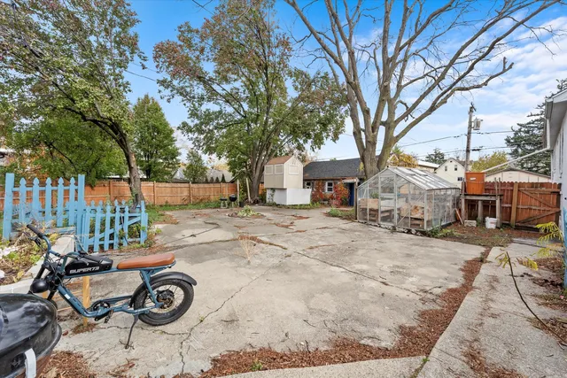 a view of a backyard with table and chairs under a large tree