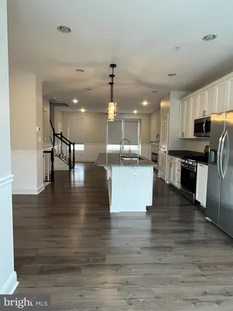 a kitchen with stainless steel appliances granite countertop a sink a counter space and wooden floor