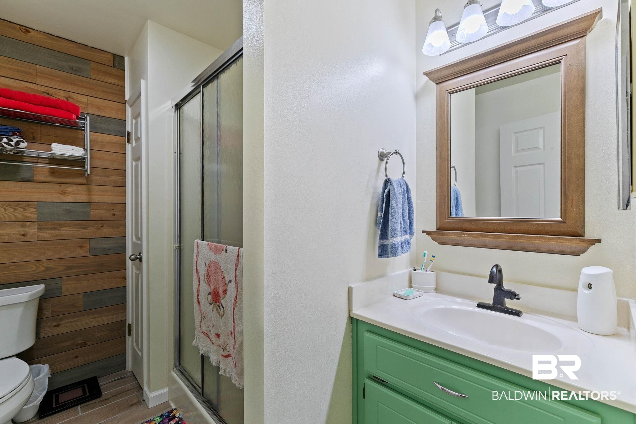 1510 South Juniper Street Foley, AL 36535 - Photo 18 of 36 Full bathroom featuring wood walls, vanity, and a stall shower